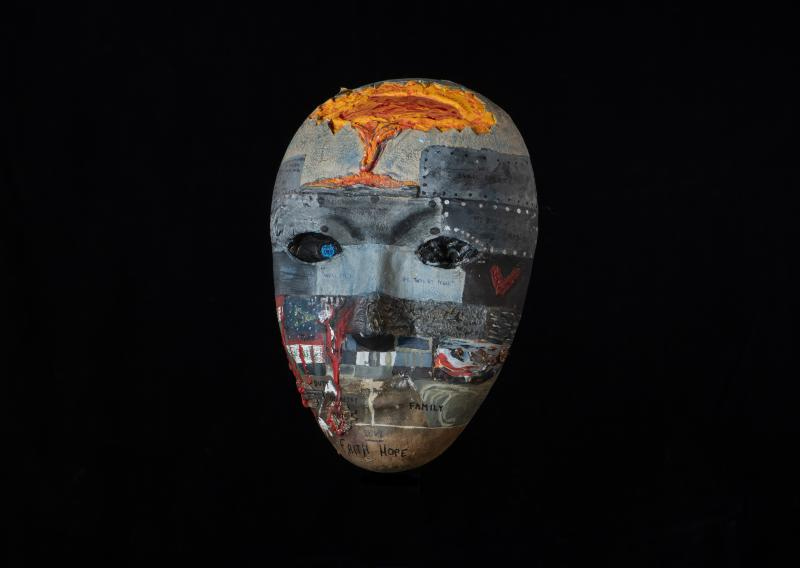 An intricately painted mask in mostly shades of grey with words of inspiration and hope 