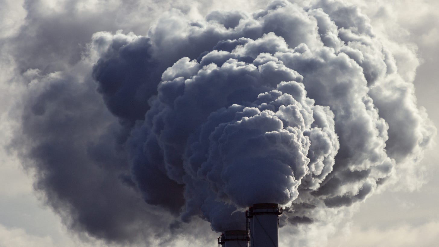 A close-up of smoke coming out of a pipe from an industrial plant, with the harmful gases being released into the air.