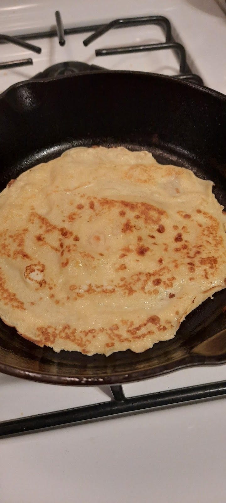 Golden and brown English pancake in a black cast iron pan.