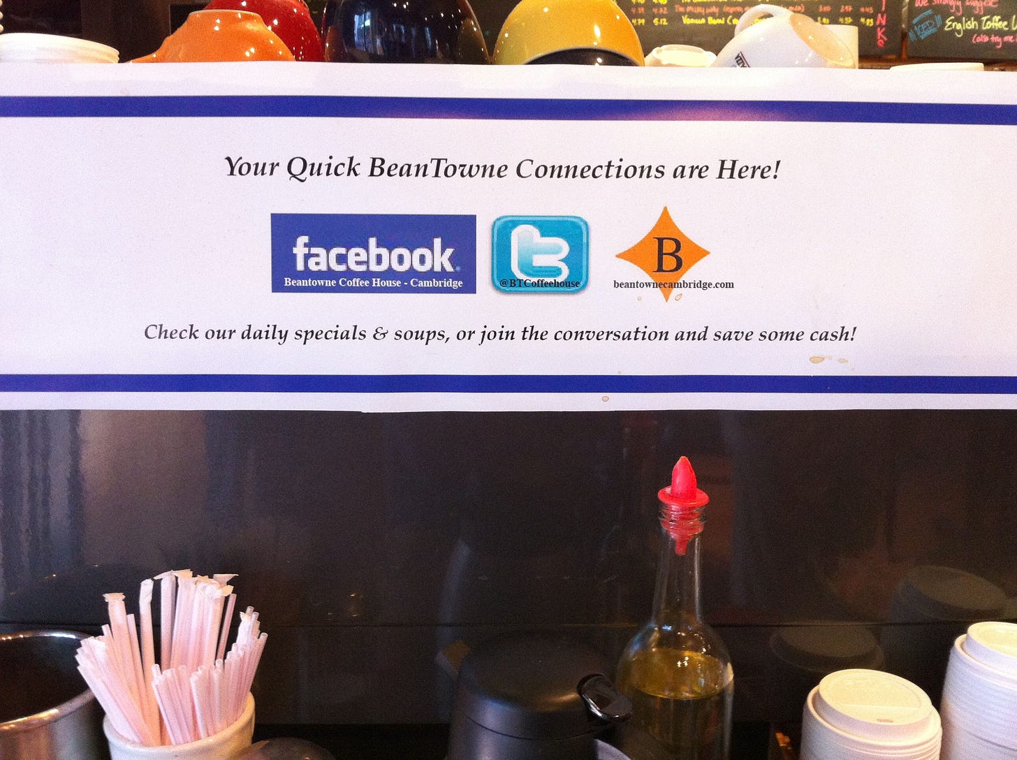 A photo of a sign in a coffee shop featuring the logos for Facebook and Twitter.