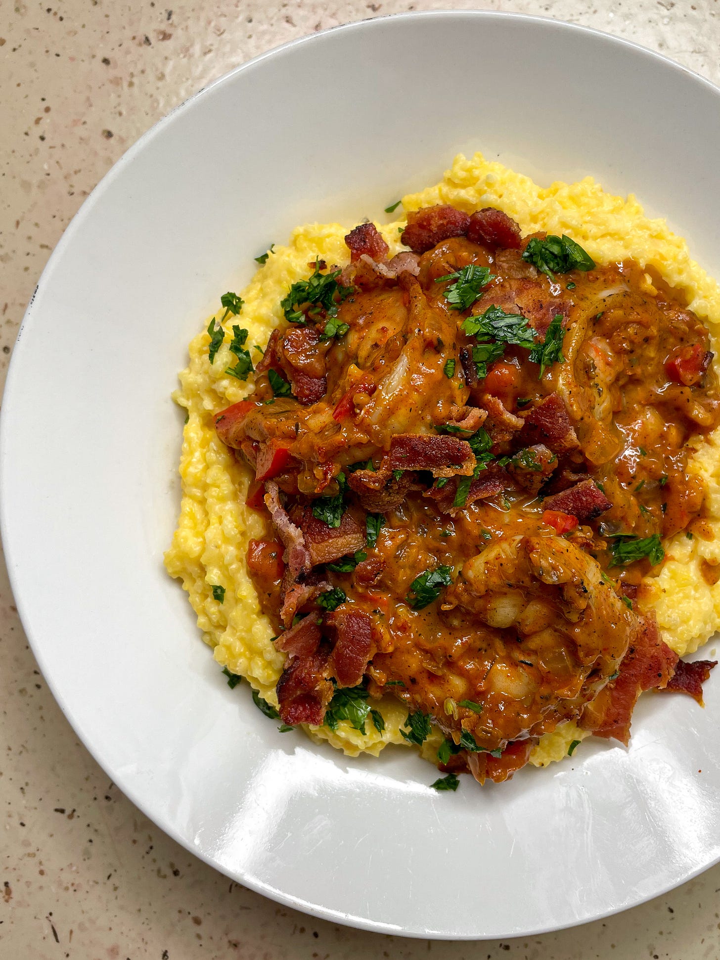 A big bowl of cheesy grits piled high with creamy, Cajun-spiced shrimp, crumbled bacon and parsley.