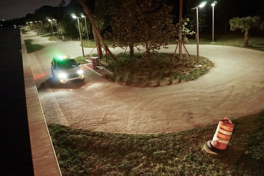 Alice Wainwright Park after dark. The park is empty except for a single vehicle with its lights on.