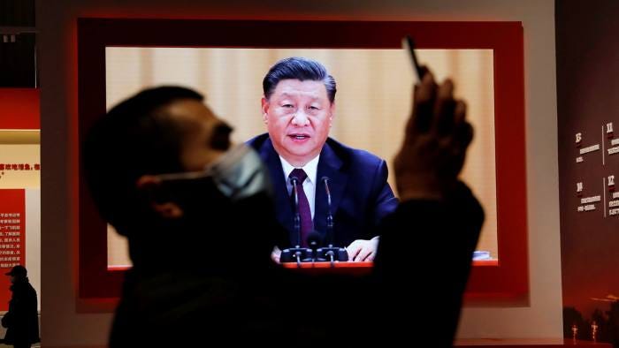 A visitor holds his mobile phone near a screen showing China’s president Xi Jinping