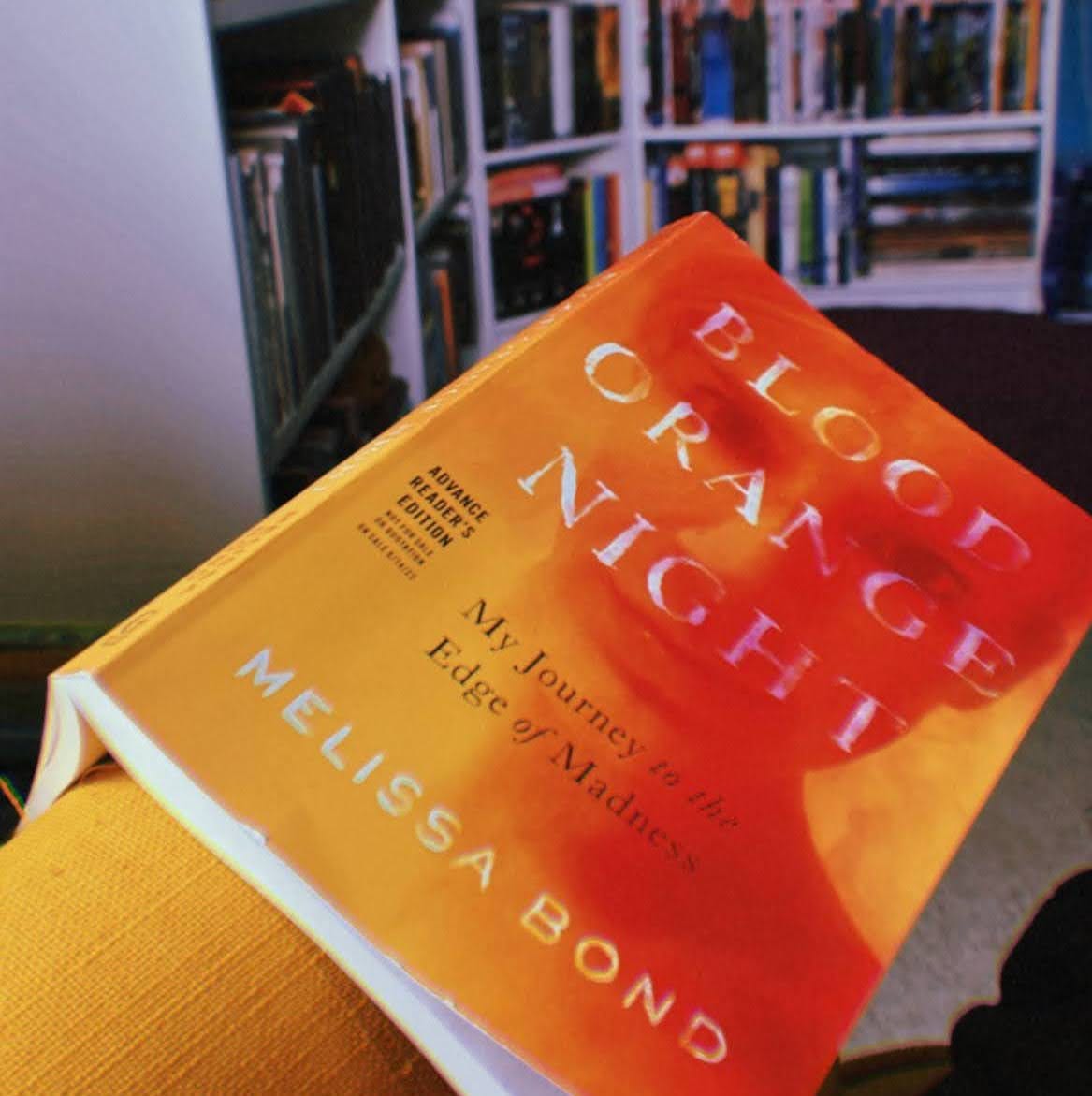 An advance reader copy of Blood Orange Night by Melissa Bond draped over a chair.