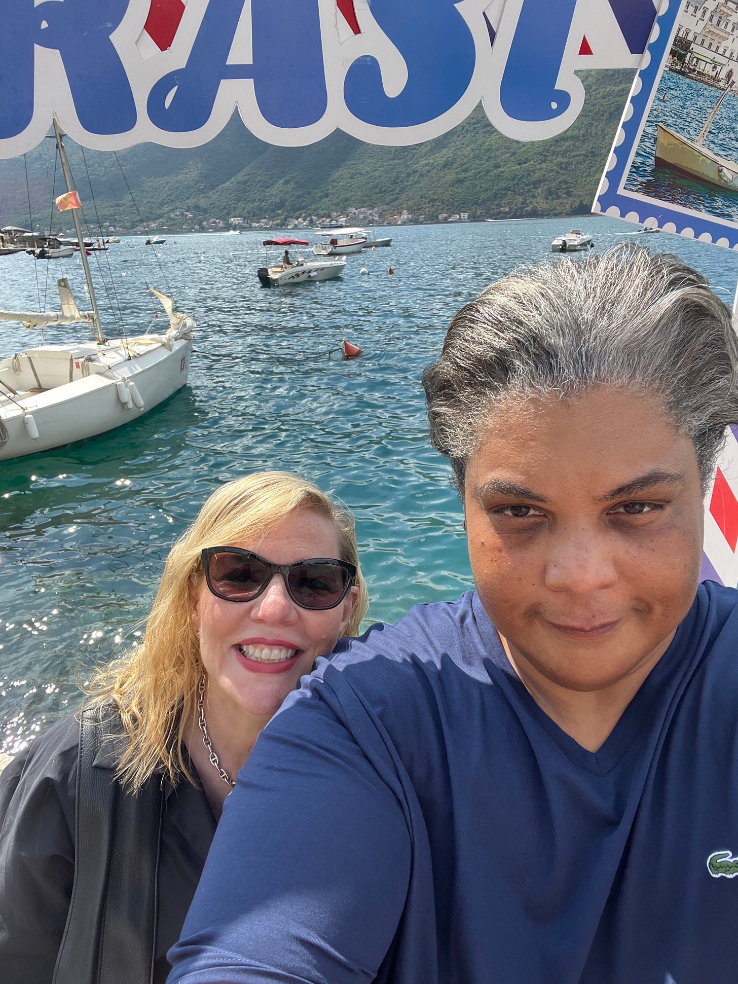 A picture of Roxane and Debbie in Montenegro. Behind them, boats in a wet dock