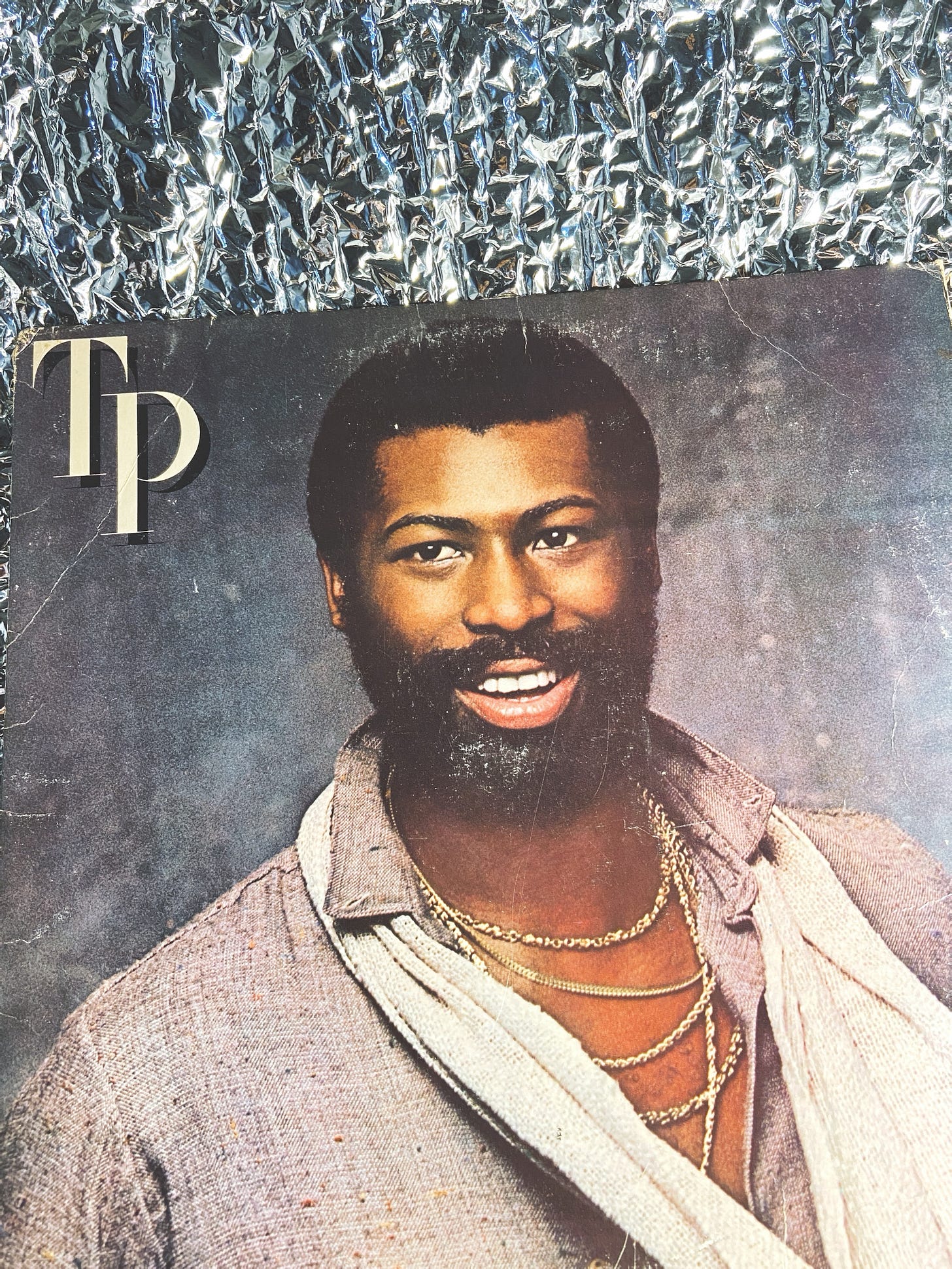 a photo of Teddy Pendergrass' 1980 record TP, placed in front of a wrinkled foil material