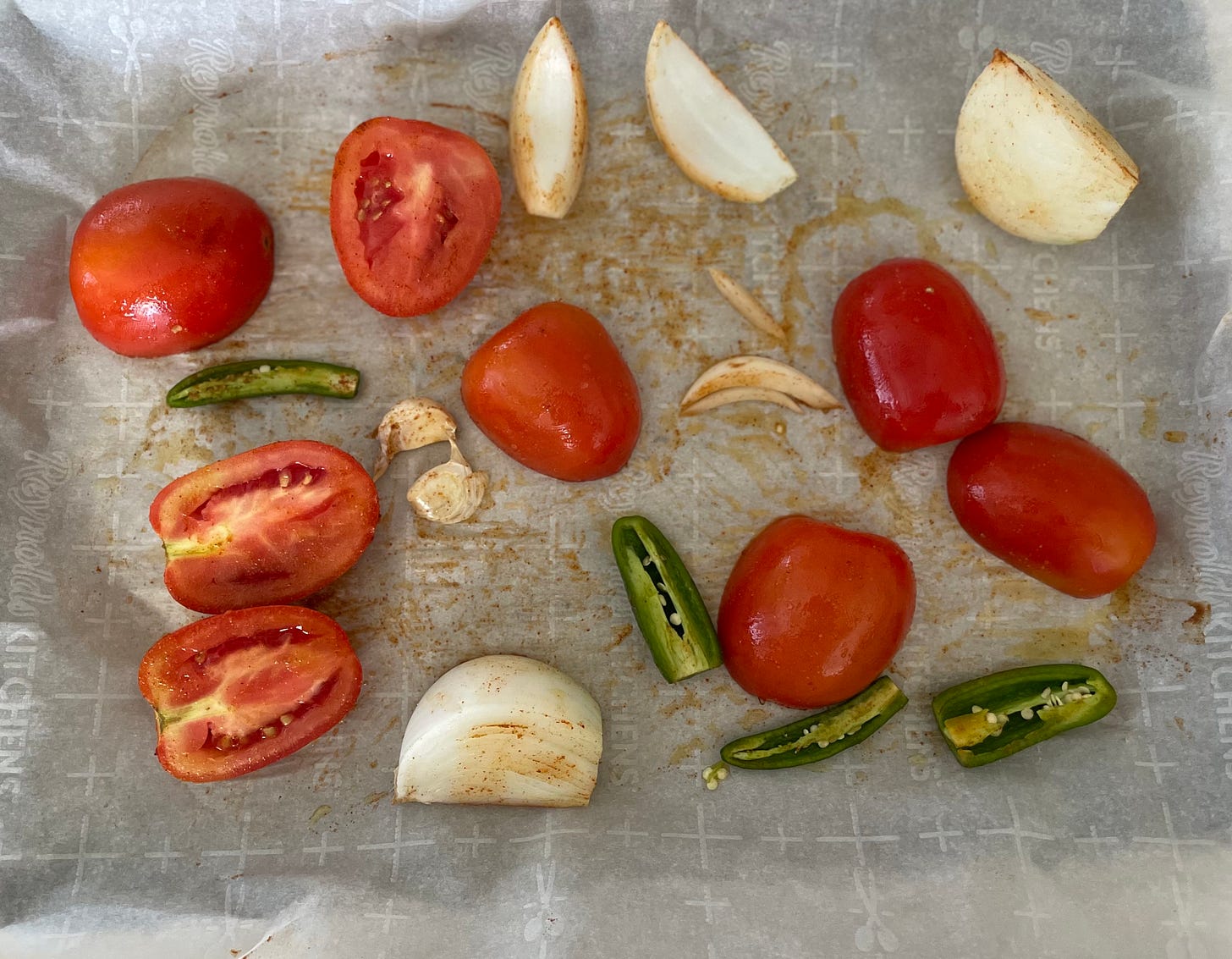 Seasoned tomatoes onions peppers and garlic on sheet tray