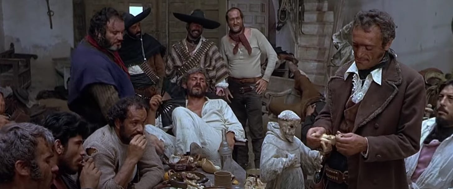 A frame for For a Few Dollars More, with El Indio in the center of his henchmen enjoying a feast in the mission they've raided. El Indio has a patchy fan in hand, waving it lazily at his face.