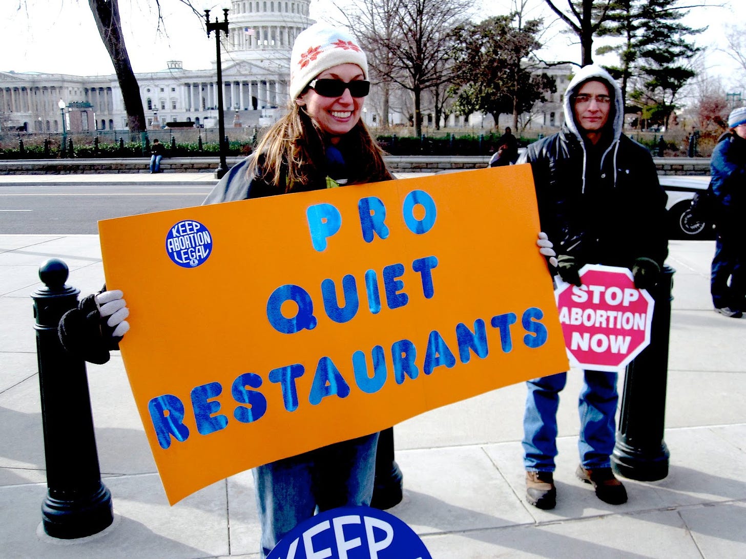 a woman holds a sign that reads pro-quiet restaurants