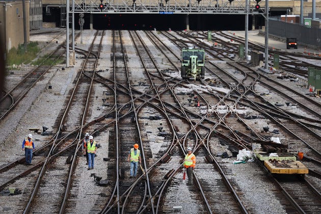 Workers service the tracks at a railroad yard.