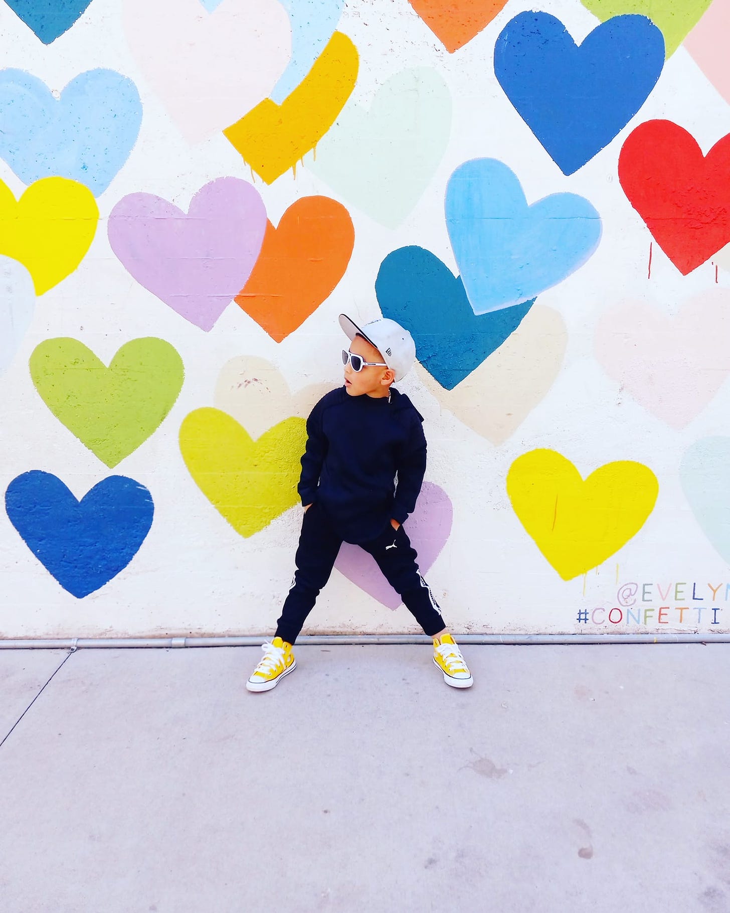 boy stands in front of heart mural