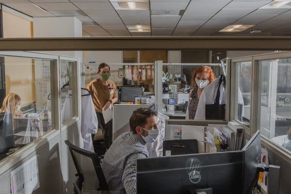 The offices of Infection Prevention at the University of California, Irvine, has translucent protective barriers between desks and now requires employees to wear masks.
