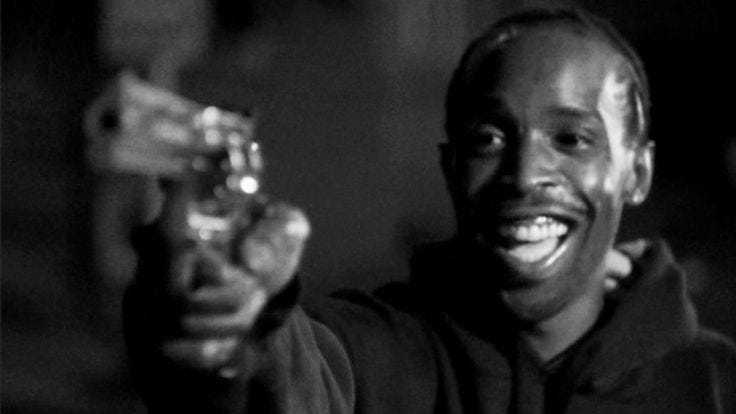Picture of Omar Little holding a pistol and smiling.