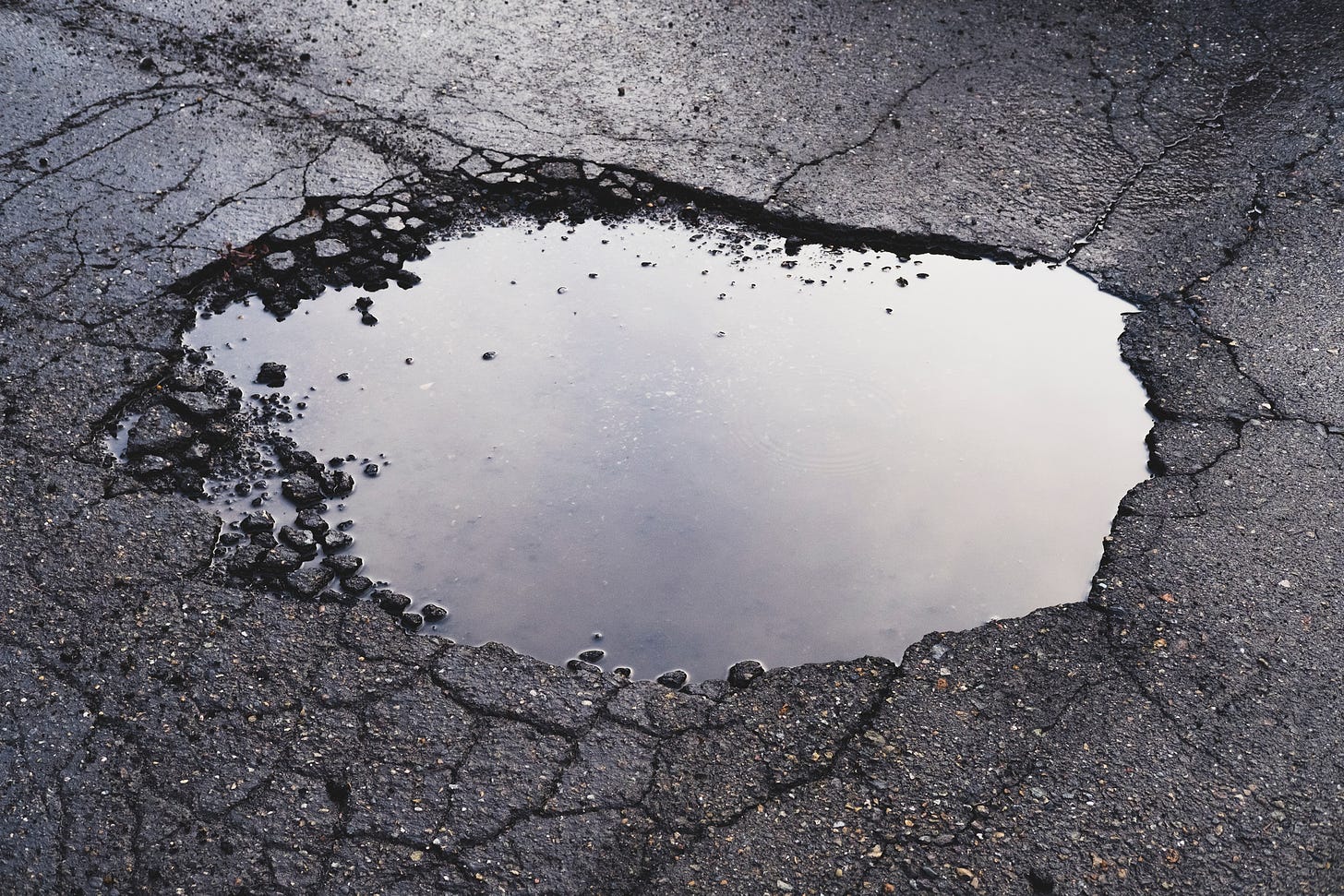 Asphalt pothole filled with water
