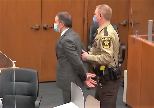 Derek Chauvin is restrained by a fellow police officer in a courtroom.