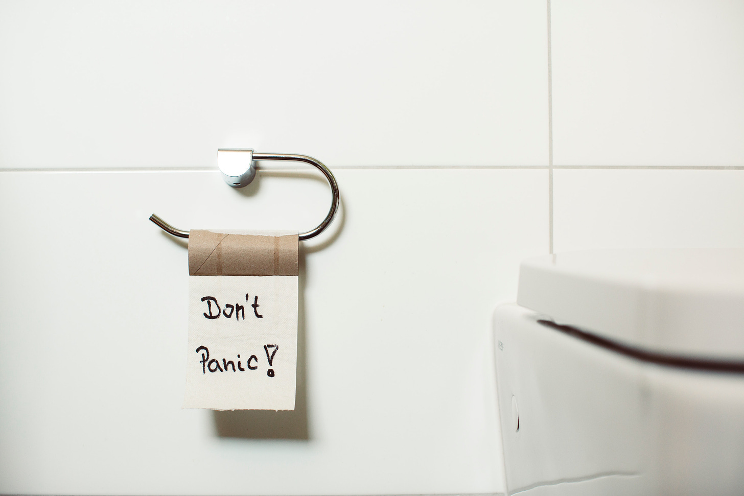 Just one sheet of toilet paper is left on the roll and it has ‘Don’t panic!’ written on it. (Photo by Markus Spiske on Unsplash)