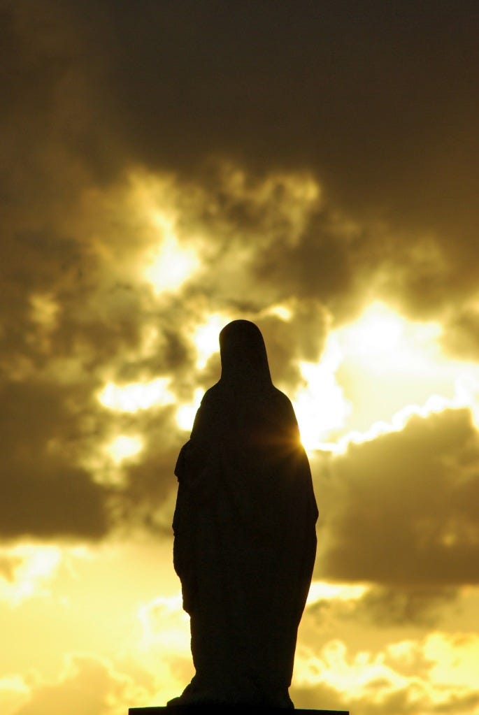 A photograph of the silhouette of a statue of Mary