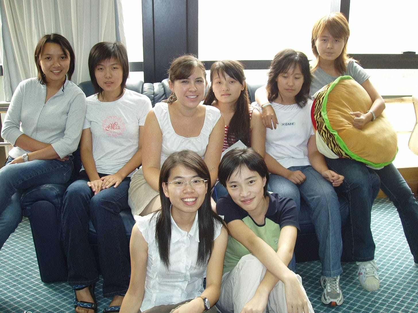 a group of Asian girls sit together on a couch in an office
