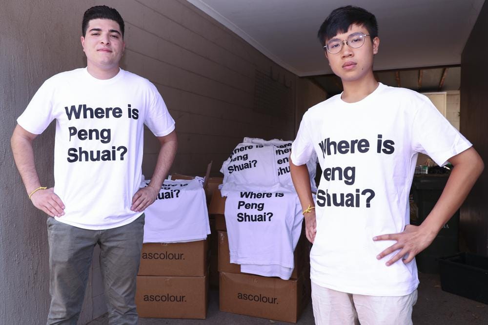 Drew Pavlou, left, and Max Mok show some of the 1,000 shirts they plan to hand out to patrons ahead of Saturday's women's singles final at the Australian Open tennis championships in Melbourne, Australia, Friday, Jan. 28, 2022. As he was being ejected for wearing a shirt with a Where is Peng Shuai? slogan, Max Mok saw an opportunity to amplify the message at the Australian Open. (AP Photo/Tertius Pickard)