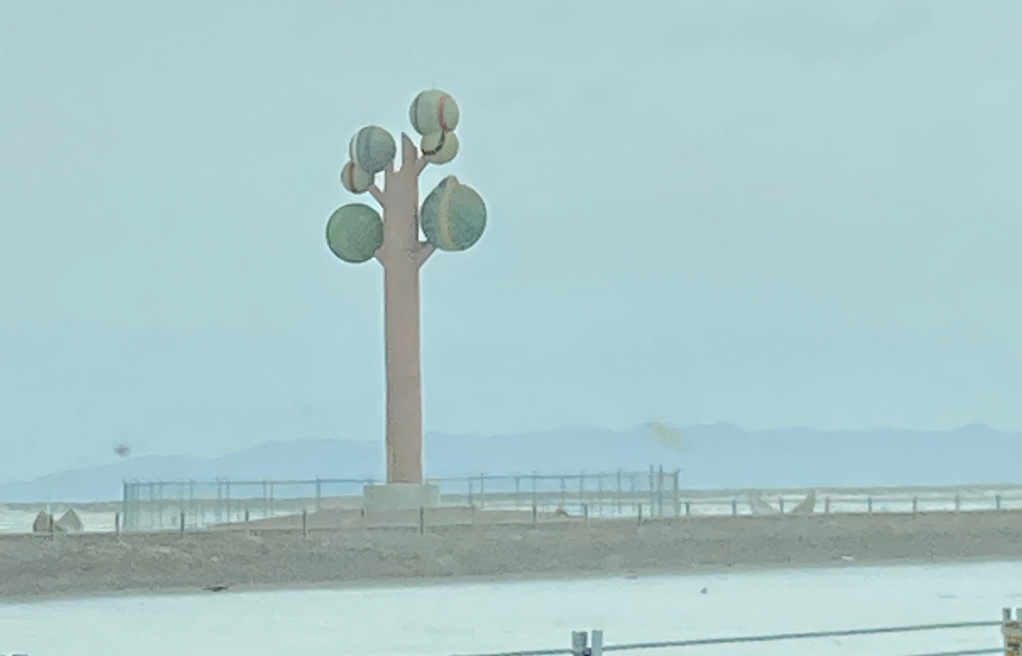 An art installation on the side of Highway 80 that looks like a giant cardboard tree, with a brown trunk and various balls (tennis, etc) for leaves.