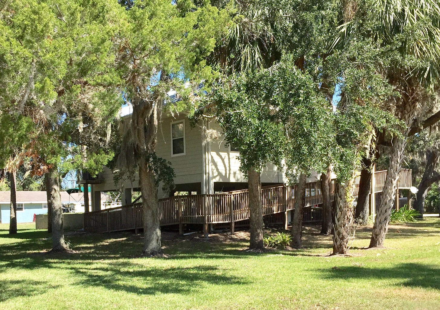 House on stilts with a wrap around ramp. Surrounded by oak trees with Spanish Moss