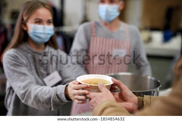 Bénévoles servant de la soupe chaude pour les sans-abri dans le centre communautaire de dons caritatifs, concept coronavirus.