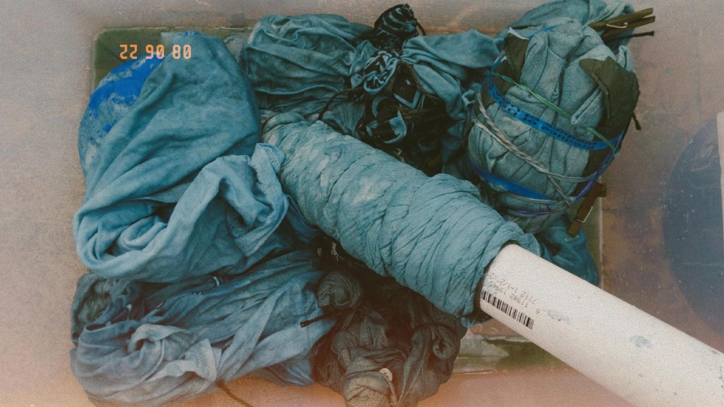 several pieces of blue clothing in a clear container, including one wrapped around a pipe