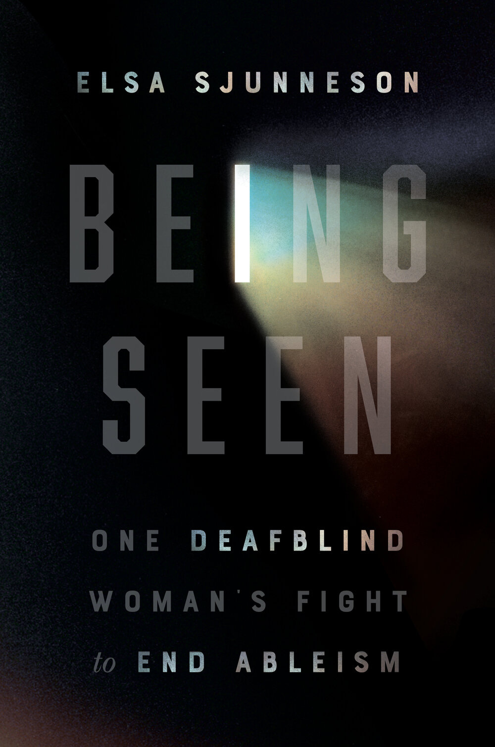 Cover image of Being Seen: One Deafblind Woman’s Fight to End Ableism by Elsa Sjunneson. From the letter “I” in “BEING,” the color of Elsa’s cataract refracts in a rainbow-colored prismatic effect over a dark background. “Deafblind” is emphasized with light.