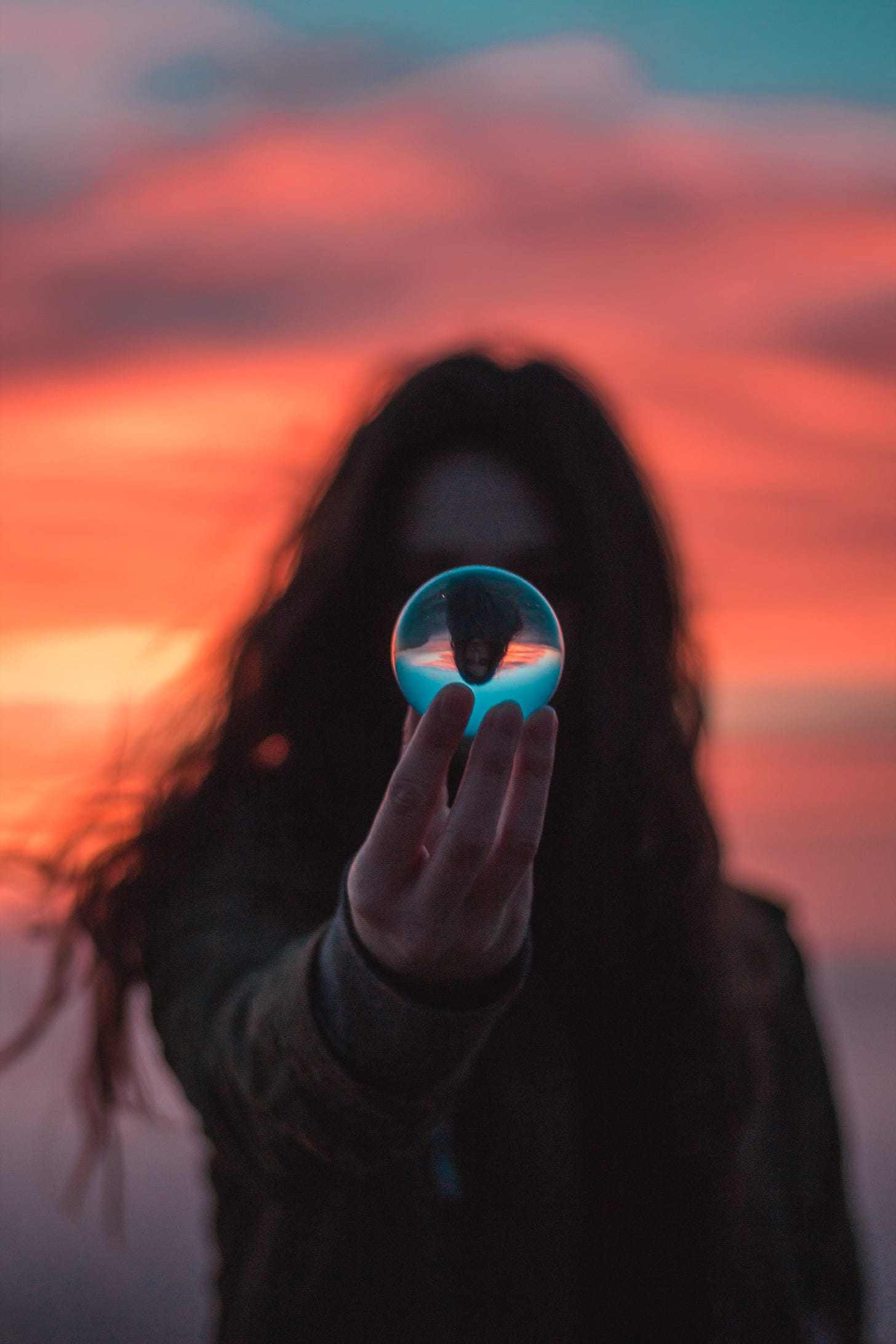 Person holding a glass ball with the sunset in the background