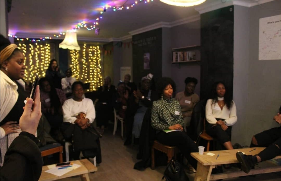 A meeting of black women sat listening to a meeting