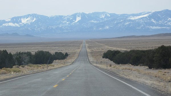 U.S. 50 west if Baker, Nevada road running through desert scrub towards snowy mountains.