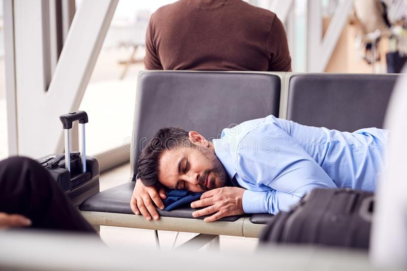 Businessman Sleeping On Seats In Airport Departure Lounge Because Of Delay stock photos