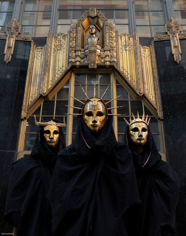 Bild von Imperial Triumphant vor Art Deco Hintergrund und mit goldenen Masken und schwarzen Umhängen