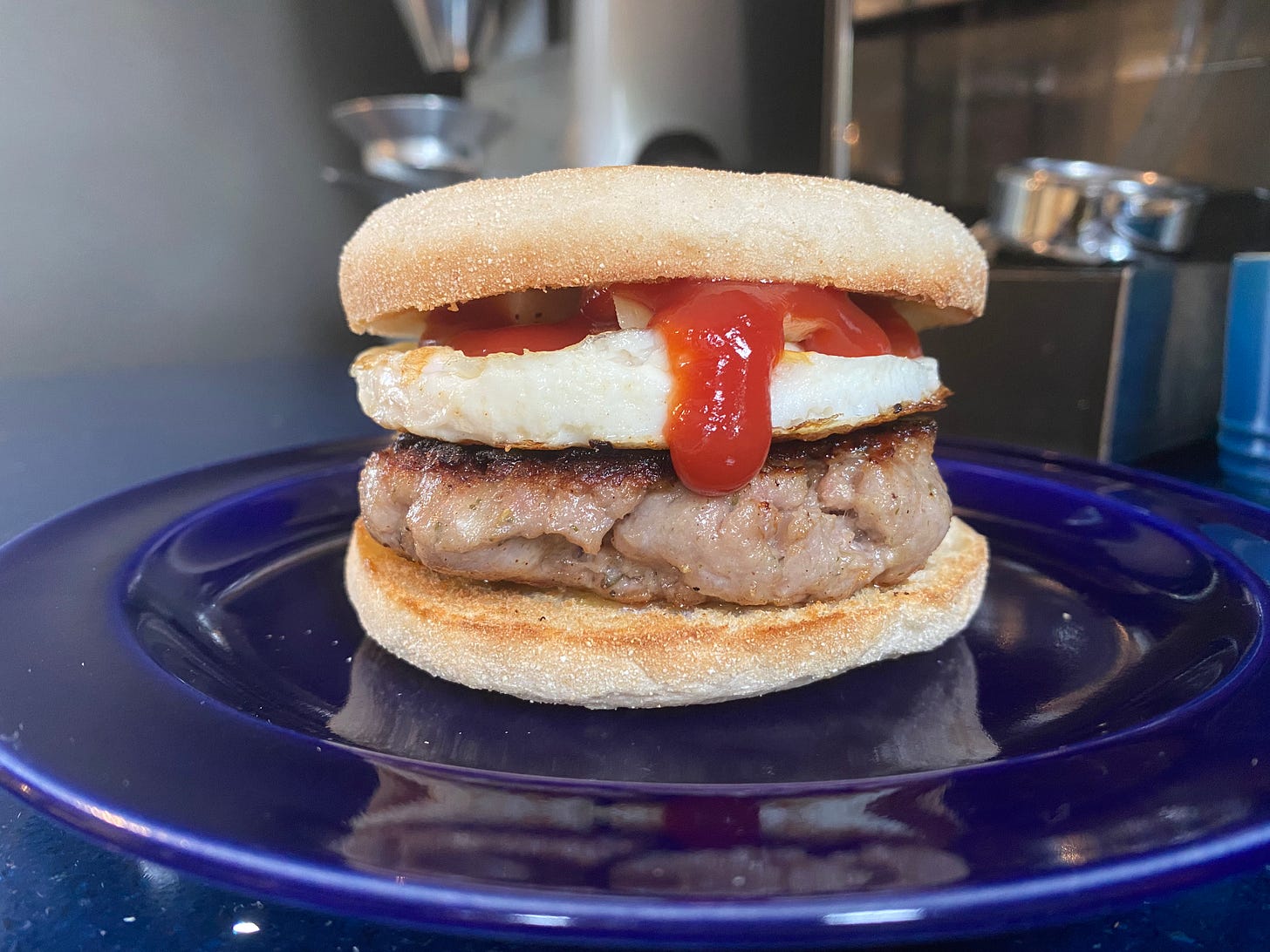 Sausage, egg and ketchup between two pieces of English muffin
