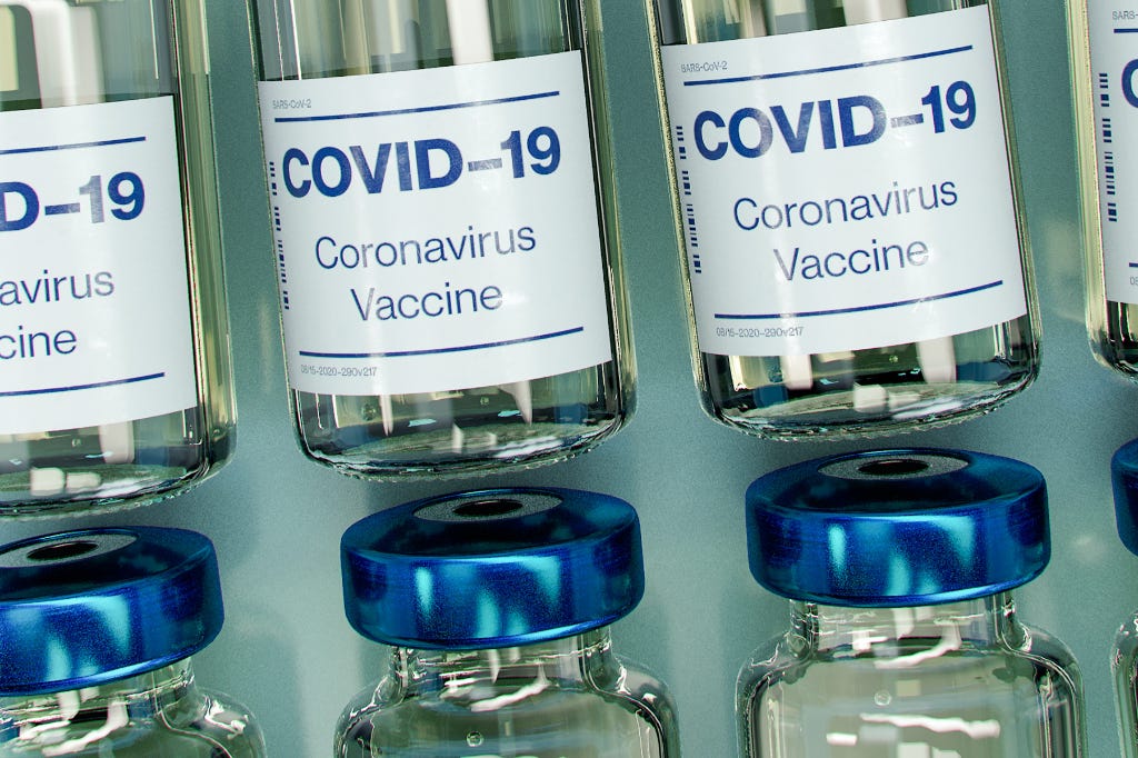 A photo of glass vials labeled "Covid-19 Vaccine"
