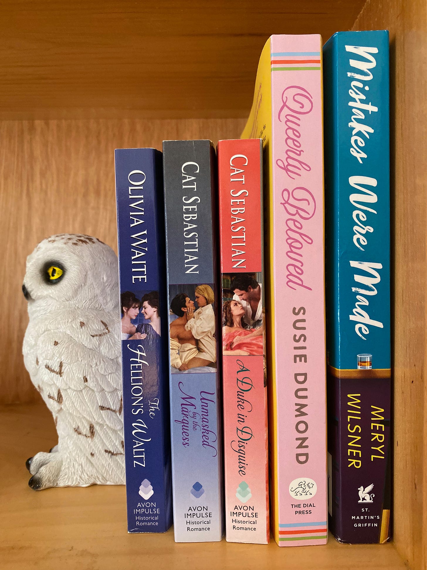 The five listed books on a shelf being supported by a snowy owl bookend.