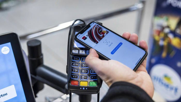 A customer uses Apple Pay mobile payment at a contactless payment terminal