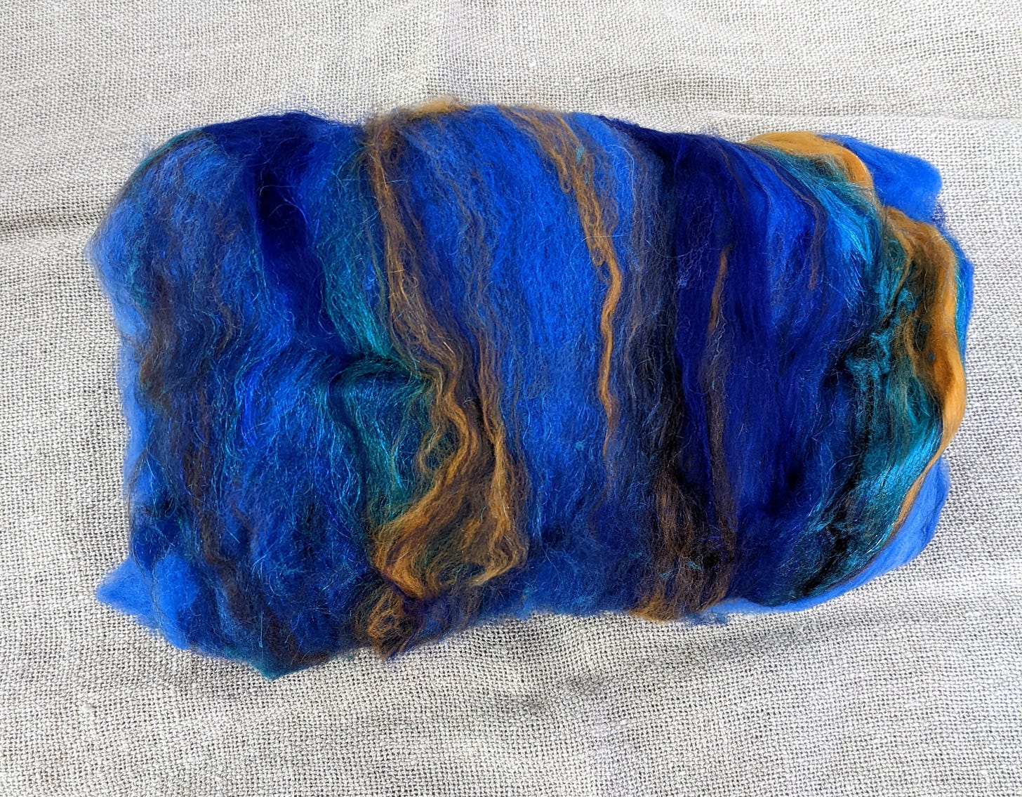 A blue batt of wool streaked with gold and teal