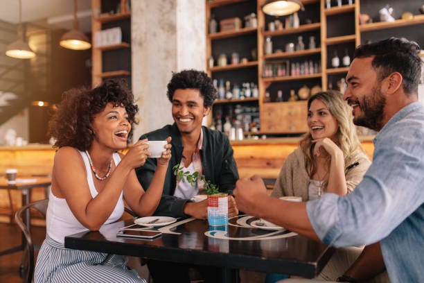 Young friends having a great time in cafe Young friends having a great time in restaurant. Multiracial group of young people sitting in a coffee shop and smiling. friends at restaurant stock pictures, royalty-free photos & images