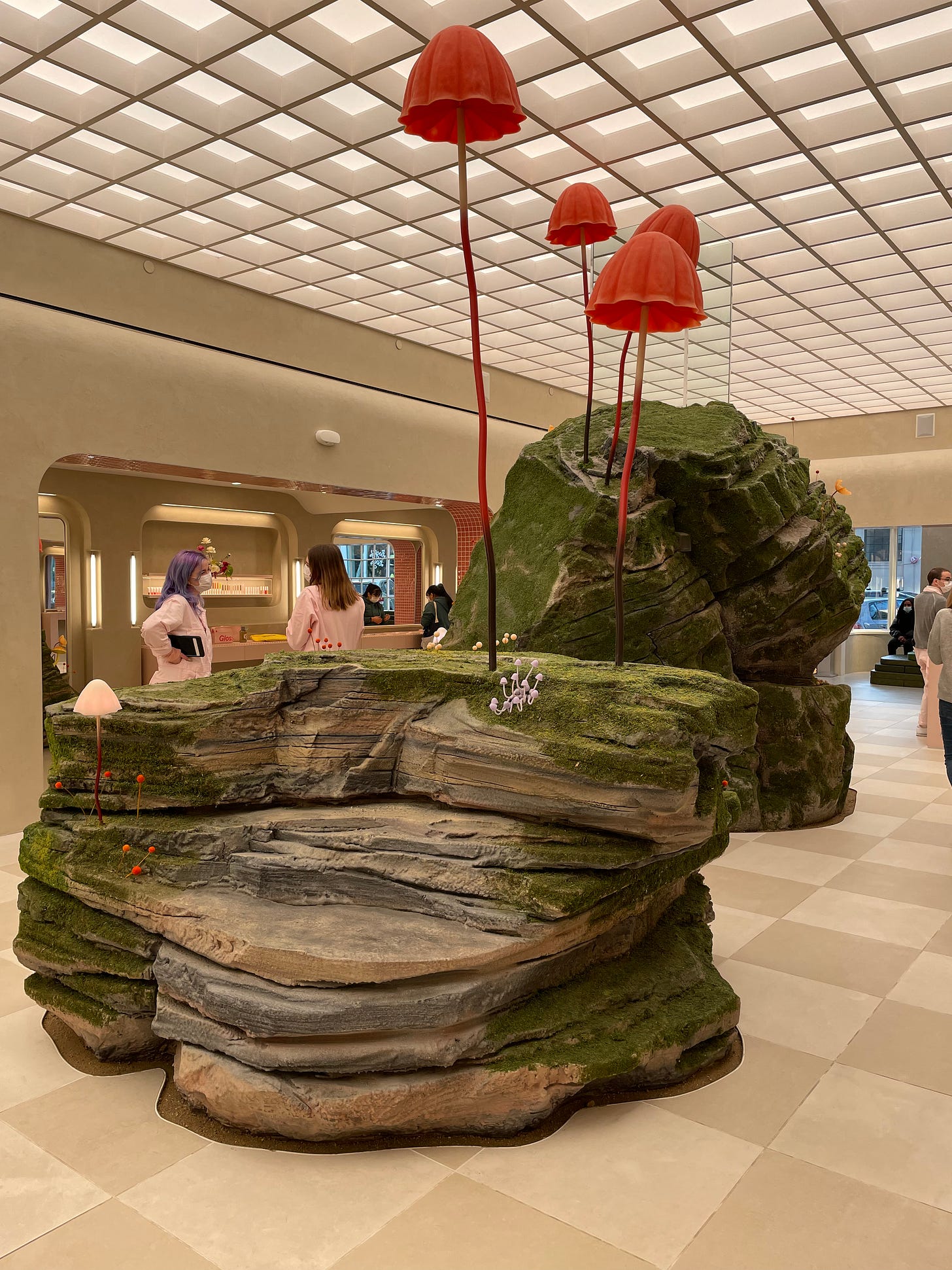 Display in Glossier store that looks like red mushrooms on top of mossy rocks