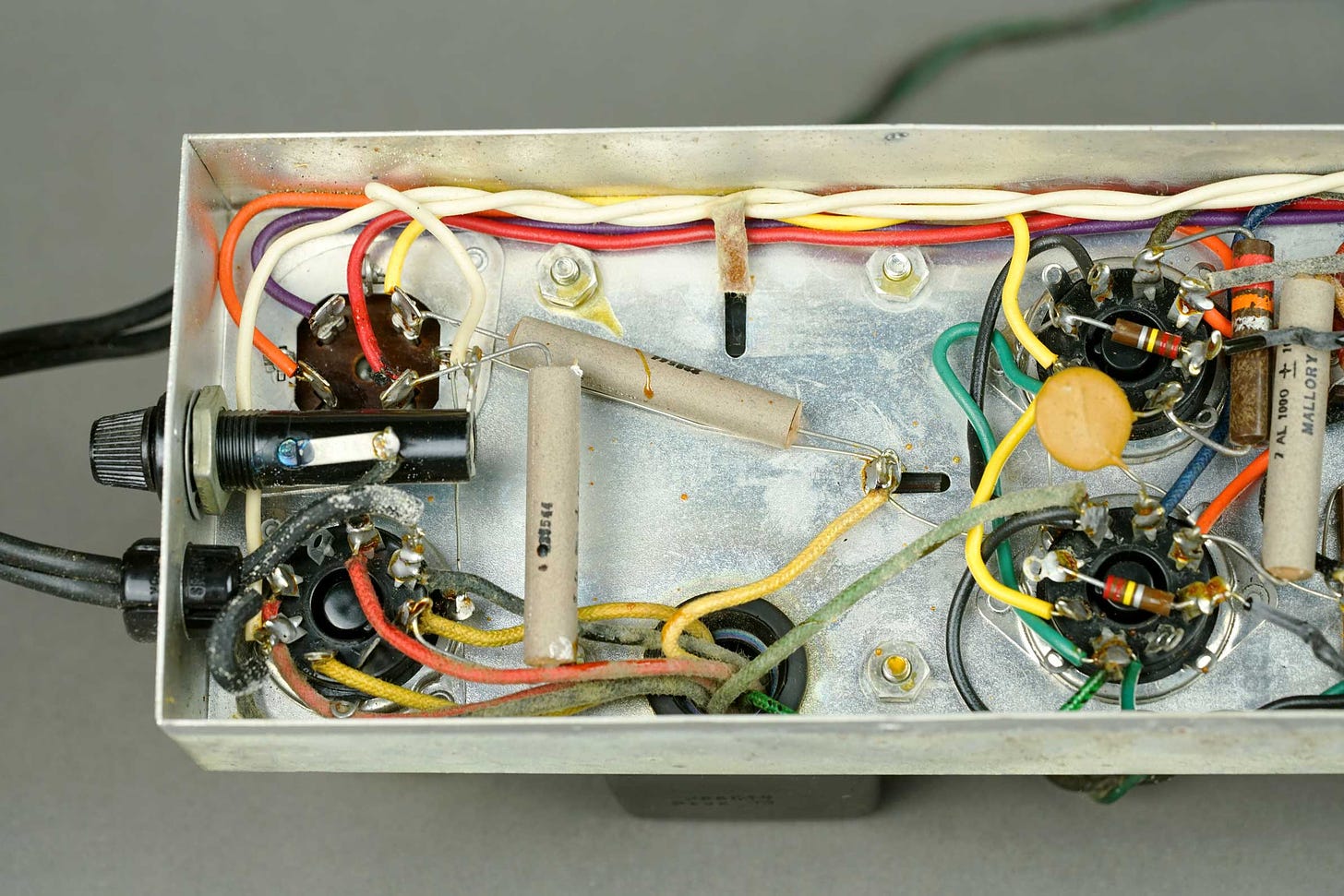 The inside of a Wurlitzer 112 amplifier, showing the rectifier tube pins, the early filter section, the power tubes and the fuse.