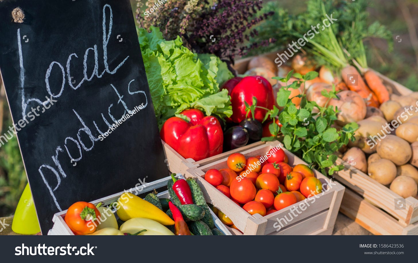 Counter with fresh vegetables and a sign of local products