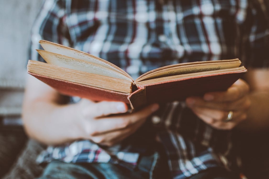 Free Person Reading Book While Sitting Stock Photo