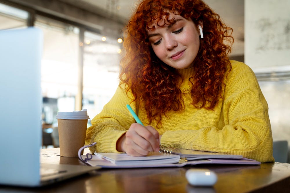 Attractive young ginger-haired lady writing her to-do list in a morning.