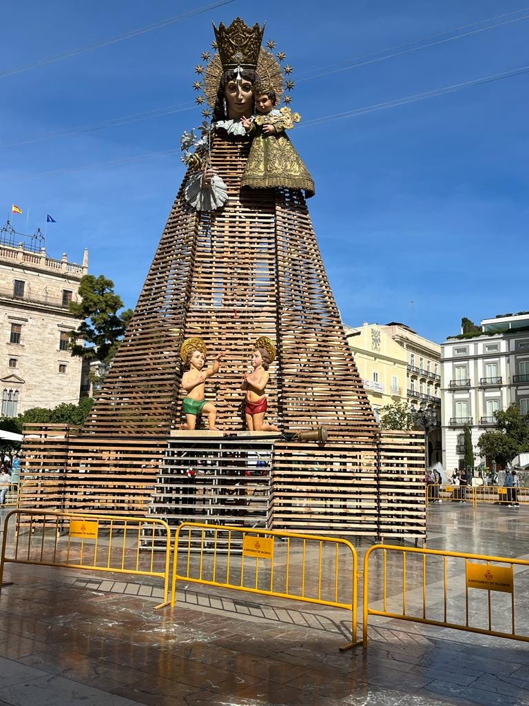 A giant statue of the Virgin Mary holding the baby Jesus - her body is made out of slats like pallets.