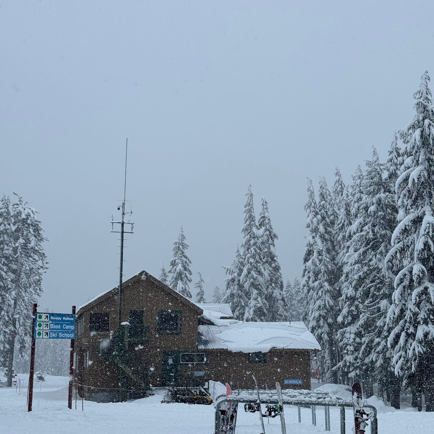 A brown building at a ski area covered in snow during a snow storm.