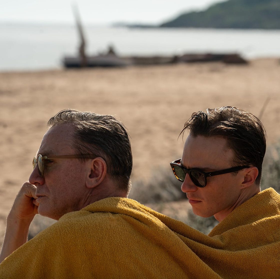 two individuals wrapped in yellow towels sitting on the beach