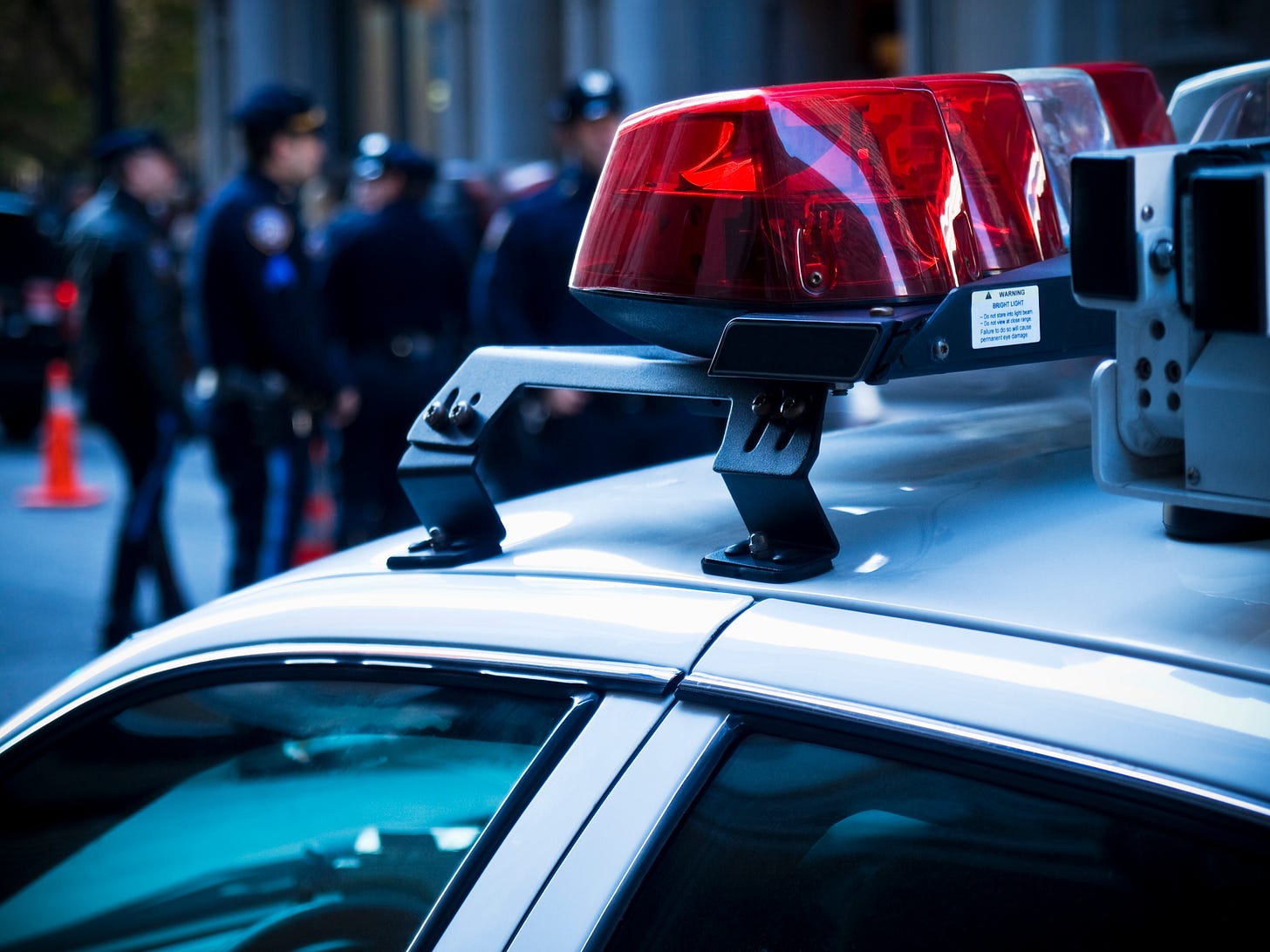 Police car with police officers blurred in the background