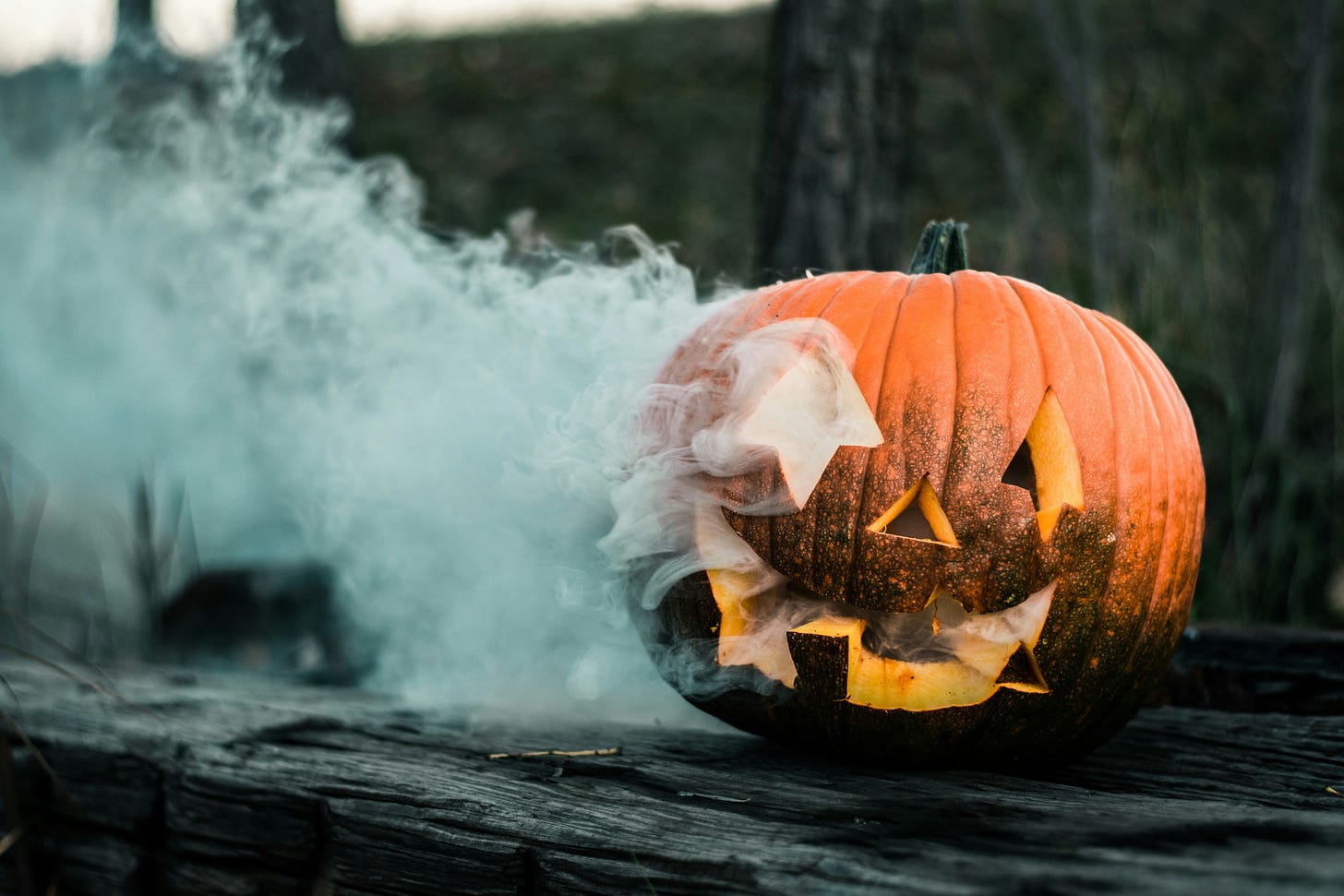 A carved, smiling jack-o-lantern spills smoke from its eyes and mouth.