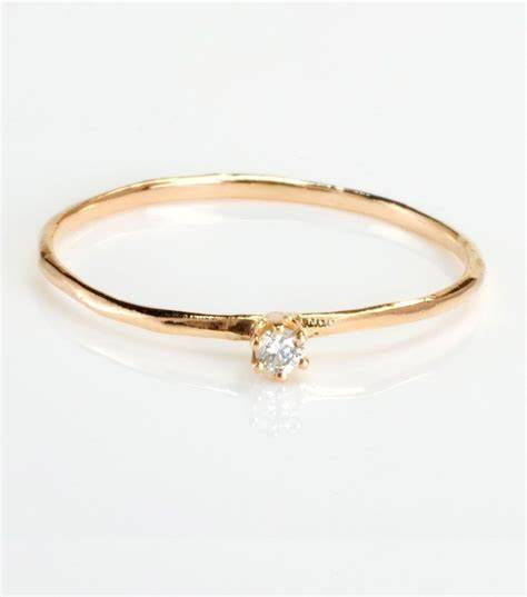 a photo of a very small simple diamond ring on a plain gold band